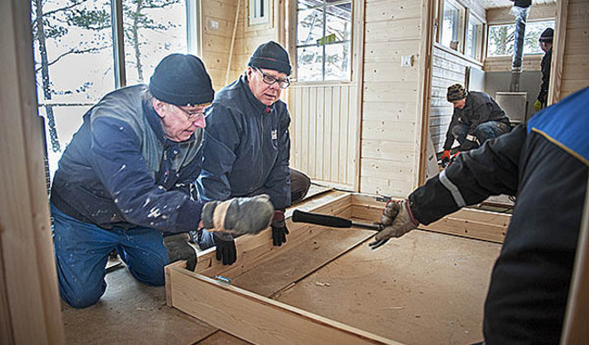 Christer Nyman och Leif Tallroth monterar ytterdörren medan Dag Granberg och Uno Höglund jobbar inne i själva bastun.